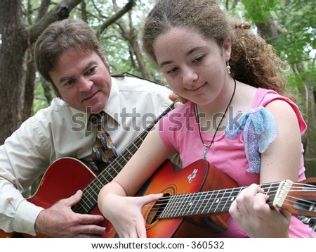 A father watching his daughter play guitar.