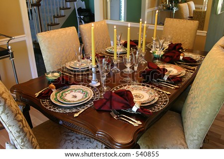 a table set with fine china and candles for the holiday meal