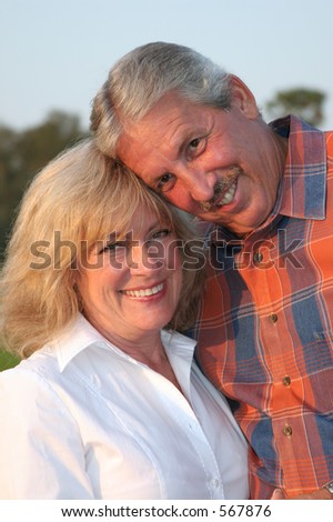 a very attractive married couple posing for a portrait in the late afternoon sun