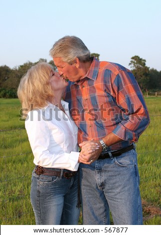 a good looking mature couple kissing in the late afternoon sun.