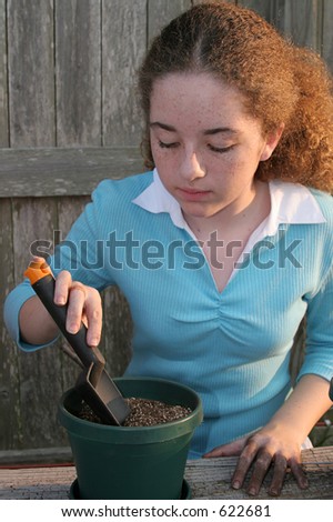 A student digging a hole in the dirt preparing to plant seeds for a science project.