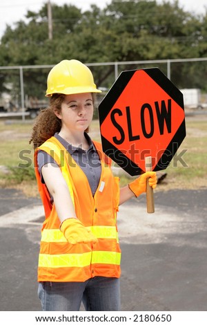 A female construction road crew member holding a slow sign for traffic.