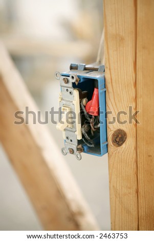 Closeup of an electrical switch box nailed to a wood beam on a construction site.  Shallow depth of field with focus on switch. Room for Text