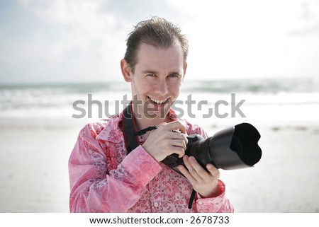 Portrait of a handsome young photographer on the beach.