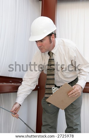 A building inspector testing the tension on a support wire in a steel frame building.