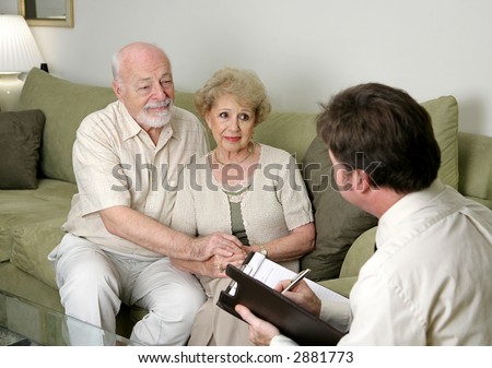 A senior couple talking with a marriage counselor.  Could also be a salesman in their home.