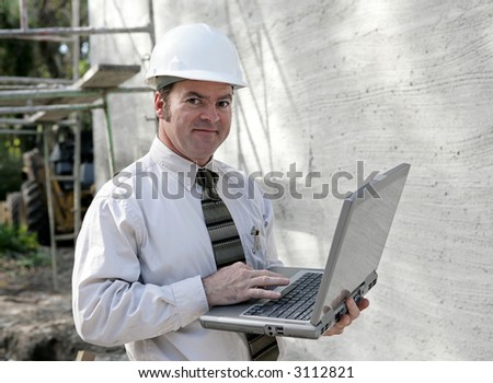 An engineer or building inspector checking building specs on his laptop computer.