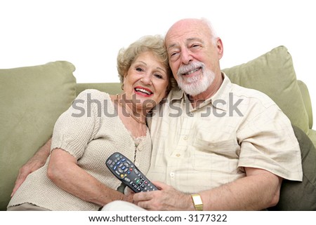 A happy senior couple watching television together. White background.