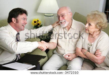 A married senior couple seeing a counselor or salesman.  The men have reached and agreement and the wife looks angry.