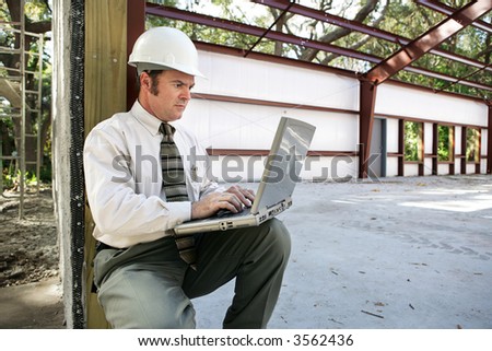 A construction engineer or inspector on the construction site with his laptop.