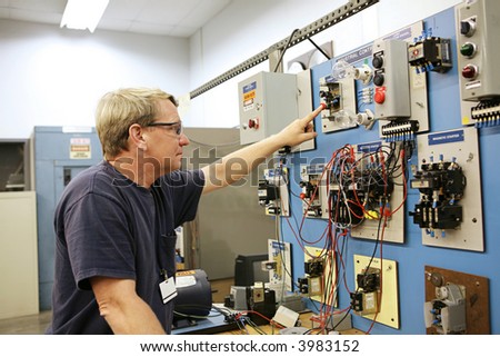 An electrical teacher working on an industrial motor control center in a classroom.