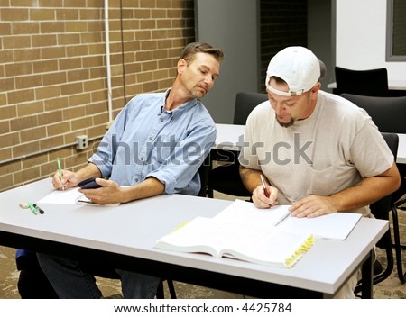 An adult education student cheating on exams by looking over another student's shoulder.