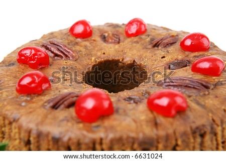 Closeup of a Christmas fruitcake.  Shallow depth of field with focus on the center of cake.  White background.