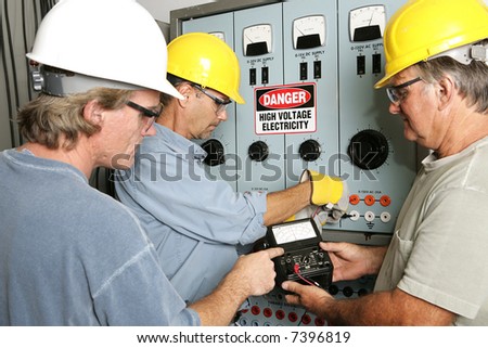 Group of electricians using an OHM meter to test voltage in an industrial power center.  All work being performed according to industry code and safety standards.