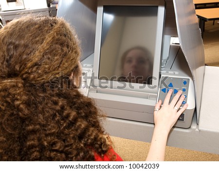 Eighteen year old girl voting for the first time on a touch screen machine.