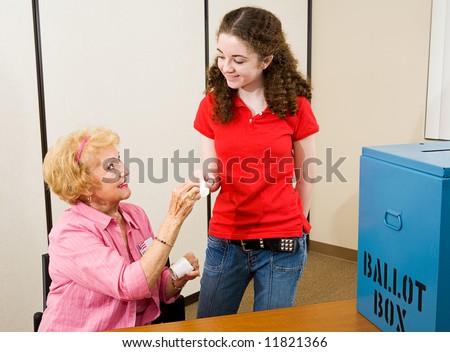 Senior woman giving an I Voted sticker to a young first time voter.