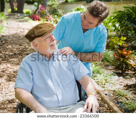 Disabled senior man in the garden with his male nurse.