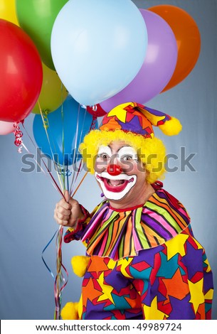 Happy clown with balloons in front of a blue background.