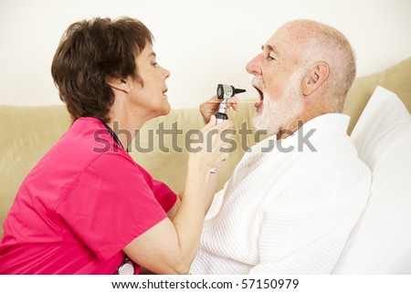 Home health care nurse uses an otoscope and tongue depressor to look in a patient\'s mouth.