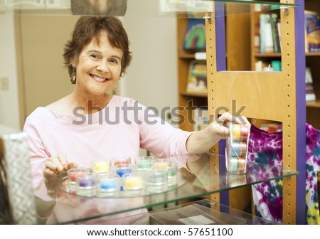 Friendly store clerk smiles as she\'s setting up a display.