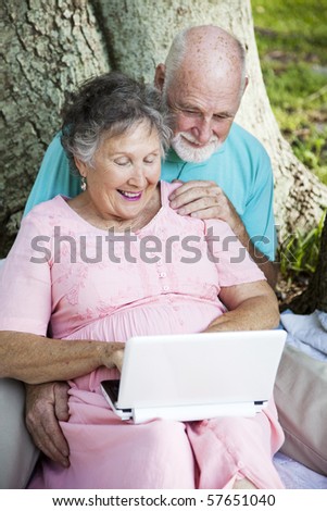 Senior couple has fun using a netbook computer in the park.