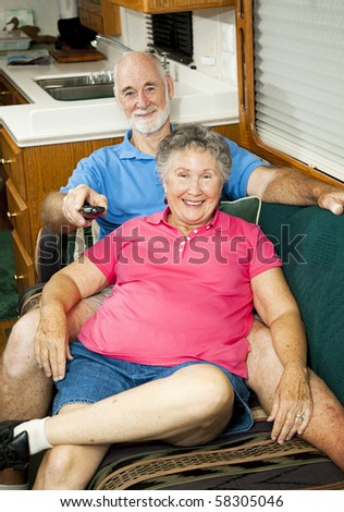 Senior couple watches TV in the cabin of their motor home.