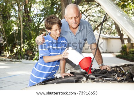Father and son changing the motor oil in the family car.