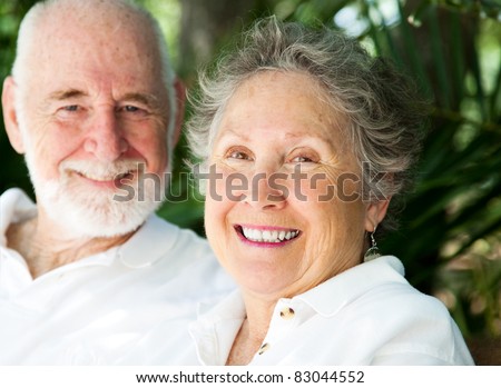 Portrait of a happy senior woman with her loving husband in background.