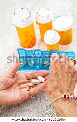 Closeup of an elderly woman\'s hands sorting her medication for the week.