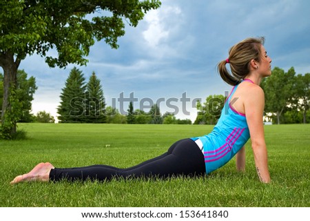 Young woman doing the Cobra Stretch/exercise in a park.