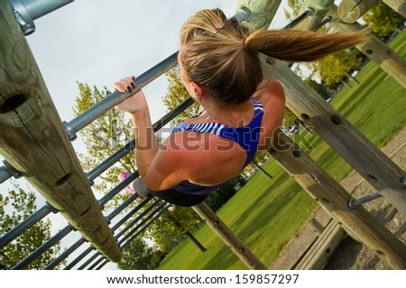Young woman doing Australian Pull-ups on a jungle gym.