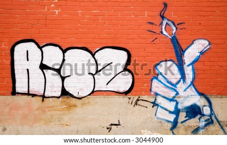 Brightly colored graffiti hand on a orange brick wall.