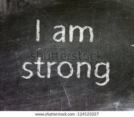 I am Strong handwritten with white chalk on a blackboard.