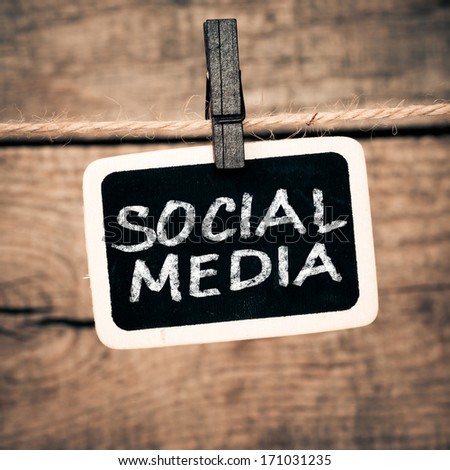 Social media concept - text on old photo and clothes peg on a wooden background