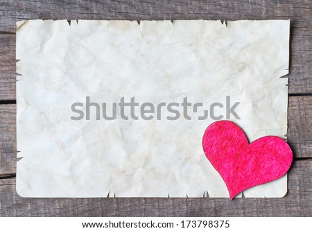 Old card on aged wood decorated with wooden heart