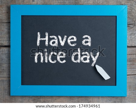 Have a nice day ! written on blue framed chalkboard on wooden background