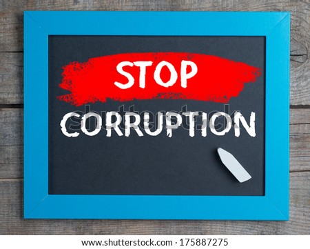 Stop corruption. Creative composition with the message stop corruption on blackboard on wooden table
