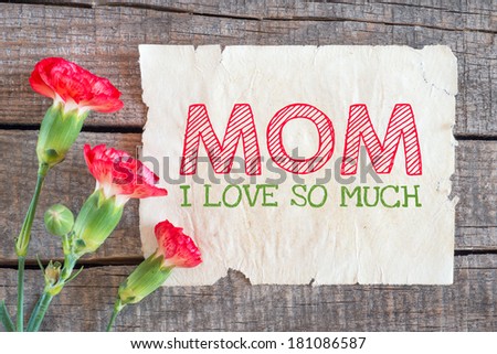 Carnation and paper with text Happy mother day,I love you so much MOM on wooden table