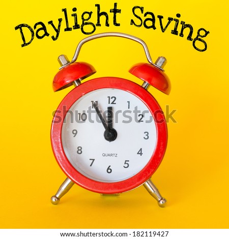 Alarm clock on yellow background with text Daylight Saving