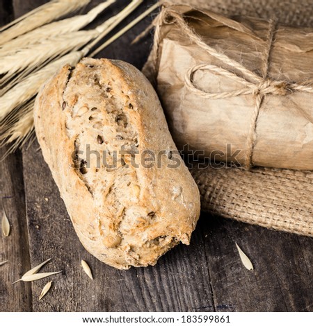 Delicious bread packed in paper on sacking on a wooden table.