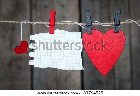 Blank instant paper and small red hearts hanging on the clothesline. On old wood background.