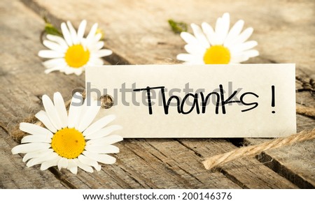 Flowers and label with lettering thanks on wooden background