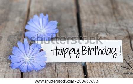 Happy Birthday card with blue chicory flowers on wooden background