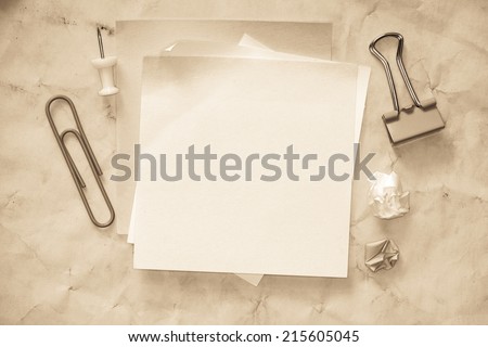 Sticky notes isolated on old paper background with clipping path pins and other office supplies . Above view.