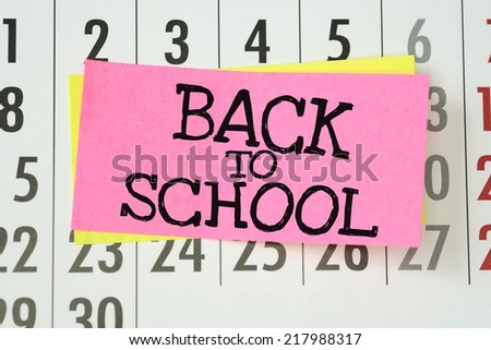 A reminder to go Back To School written on sticky paper note and stuck on a wall calendar background