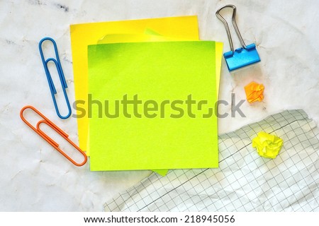 Blank yellow sticky note against background of white crumpled notes