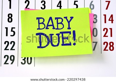 A reminder for when the baby is due written on paper sticky note and stuck to a wall calendar background