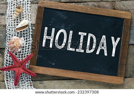 Blackboard with Holiday inscription and shells on wooden background