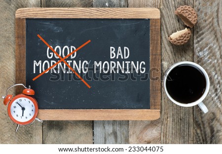 Good morning crossed and bad morning sign on blackboard with cup of coffee ,cookie and clock on wooden background