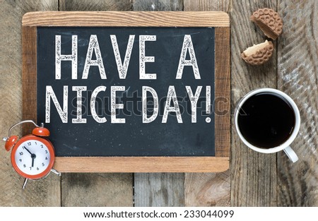 Have a nice day sign on blackboard with cup of coffee ,cookie and clock on wooden background